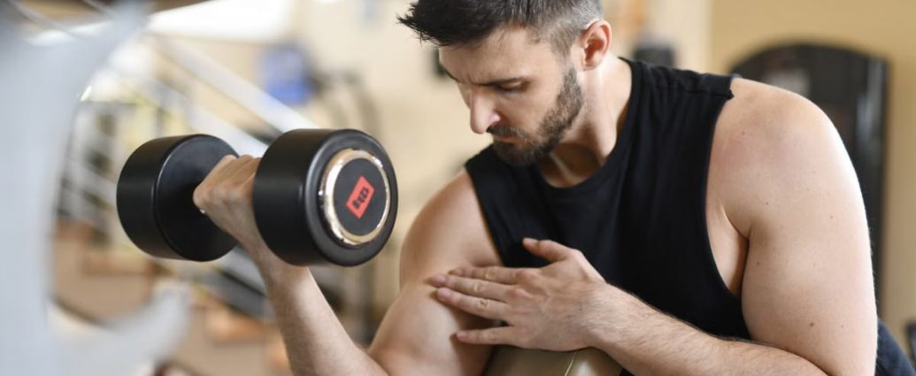 Focused man lifting dumbbell, showcasing strength and fitness indoors.